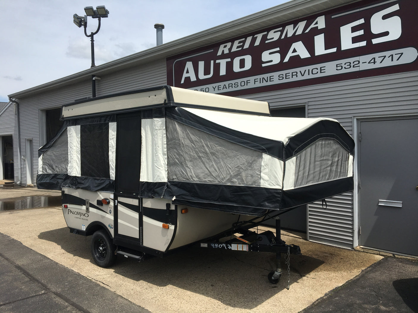 A Palomino pop-up camper, suitable for RV rental, is parked outside Reitsma Auto Sales.