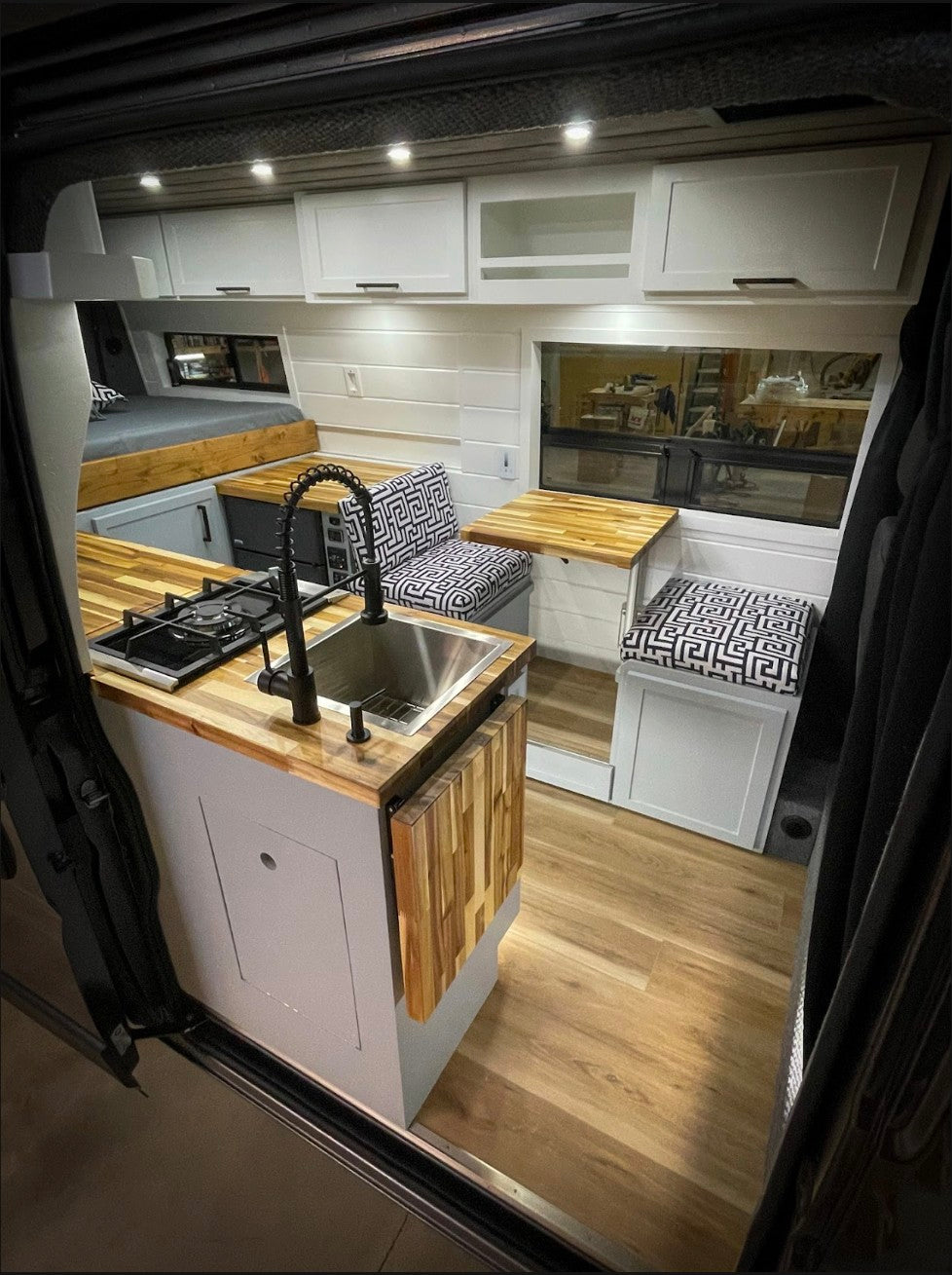 Inside a stylish RV rental: light-filled space with a compact kitchen, seating, and bed for your travels.