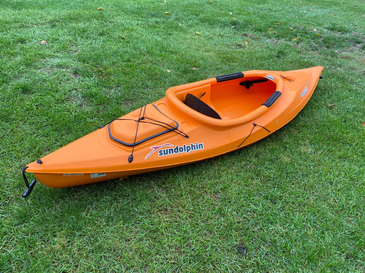 Bright orange Sundolphin kayak on green grass. Ideal for adding adventure to your RV rental trip!