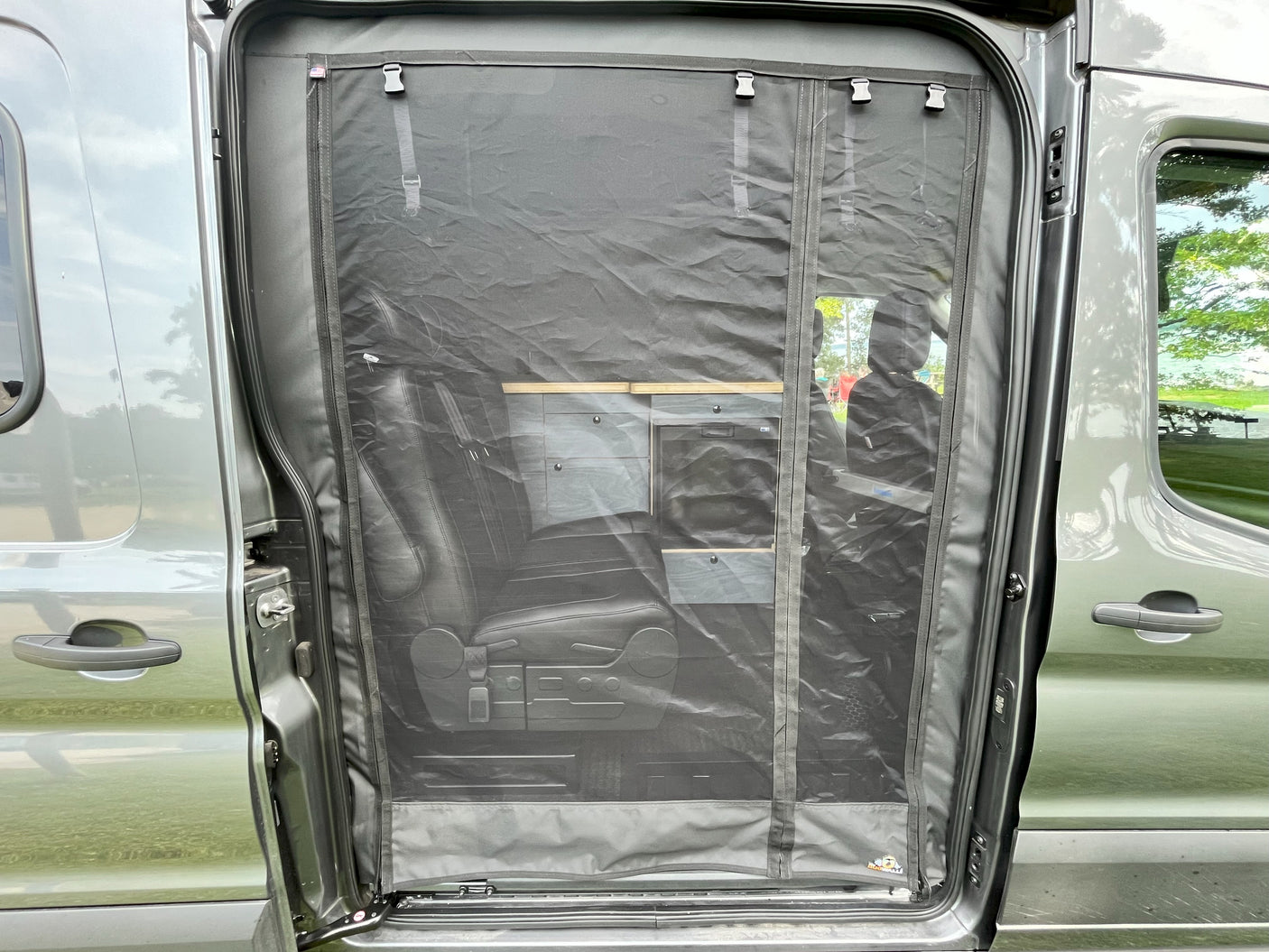 RV rental van with a full-size mesh bug screen installed in the side door, revealing interior conversion elements.