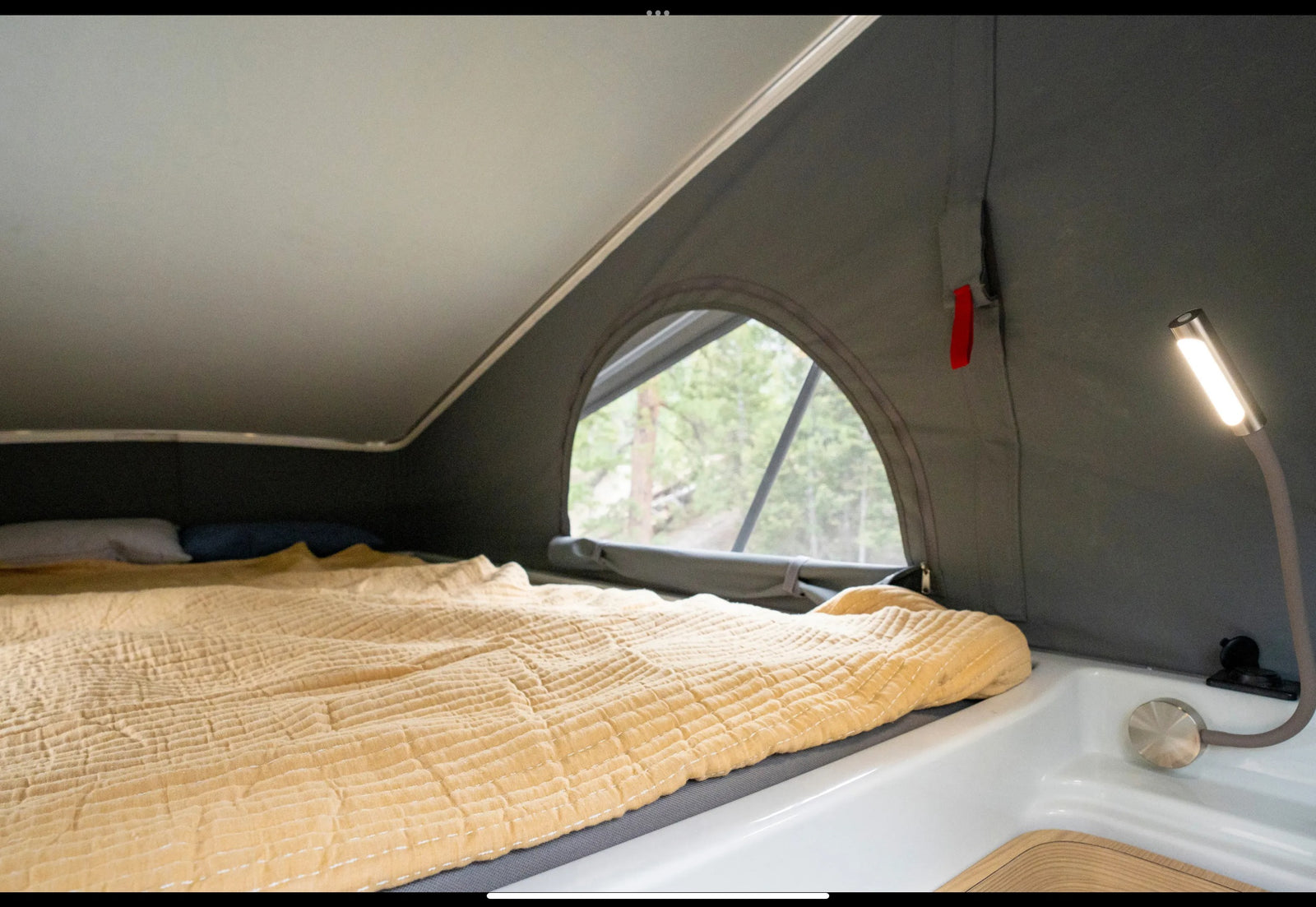 and dining area in a light wood interior.|Cozy RV rental bedroom with a comfy bed and a beautiful forest view through the open rear doors.|Detailed overhead view of an RV rental's interior