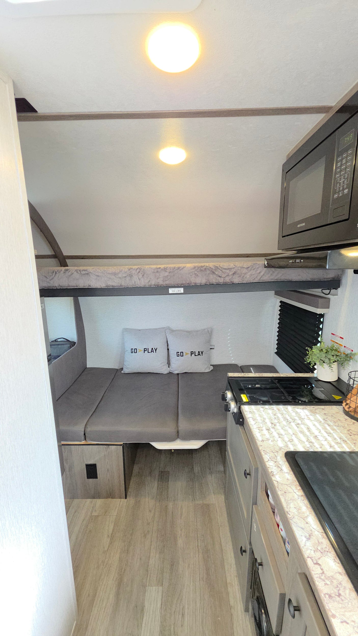 Compact rv rental interior features a bunk bed, convertible dinette, and kitchen with microwave/stove for small group travel.
