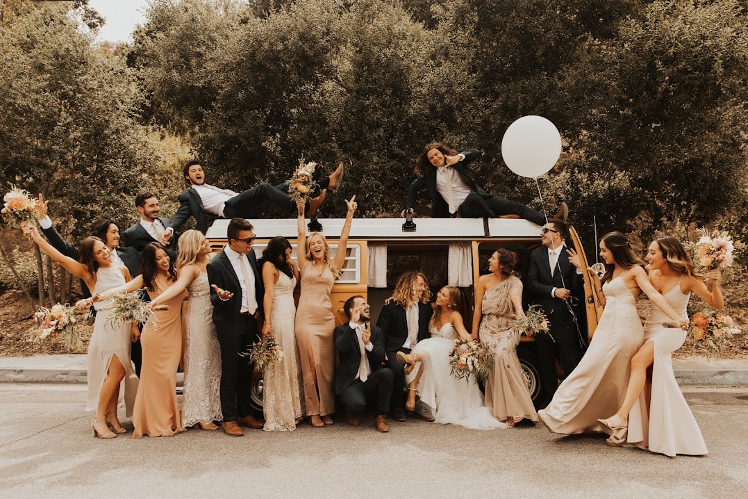 A joyous wedding party celebrates with an RV rental van, striking fun poses. Some are even on the roof! — photo 4