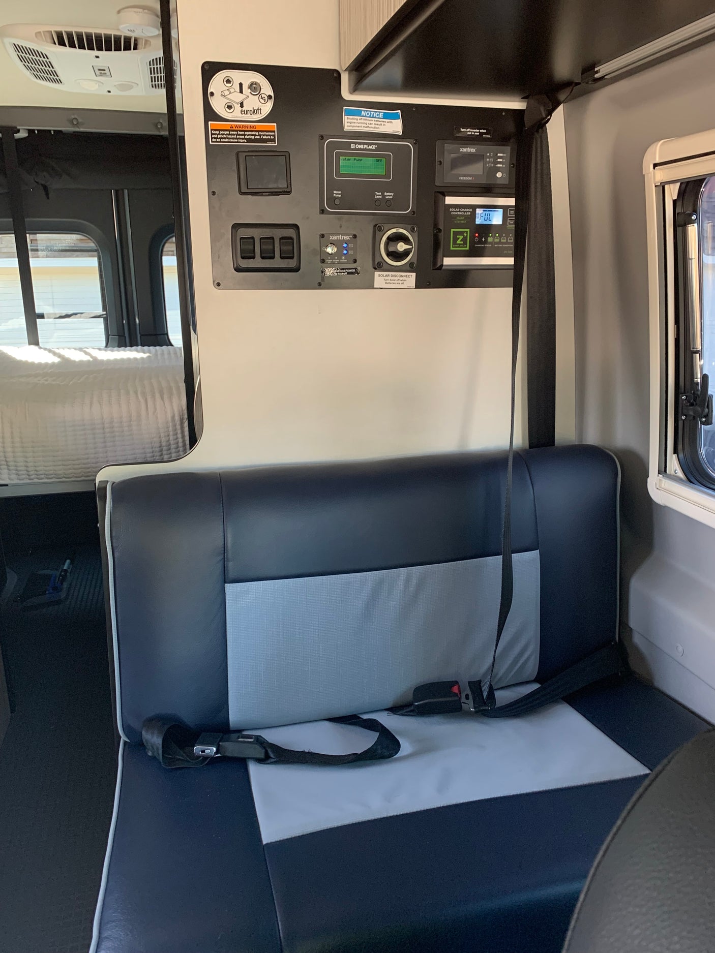 RV rental interior: A detailed view of the RV's control panel, showing power, water, and solar readouts, next to comfortable seating and a bed.