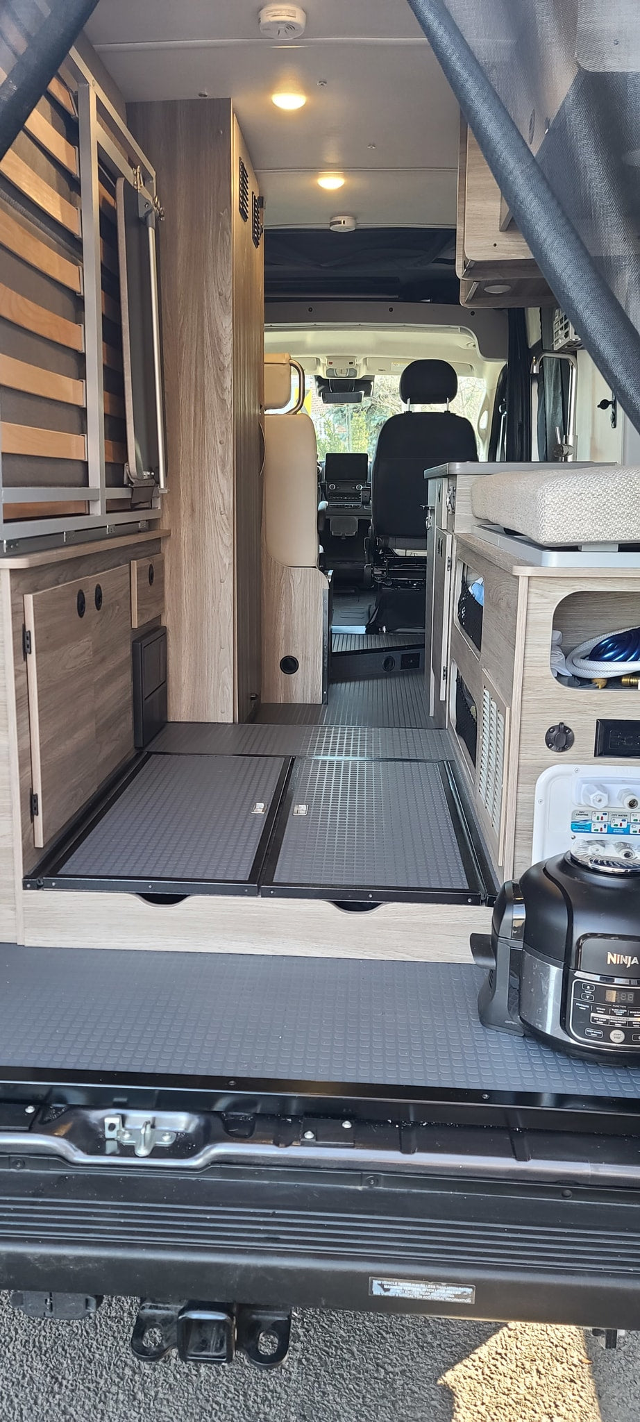 parked on a palm-lined street in a vibrant city scene.|Modern RV rental van parked on a brick herringbone patio