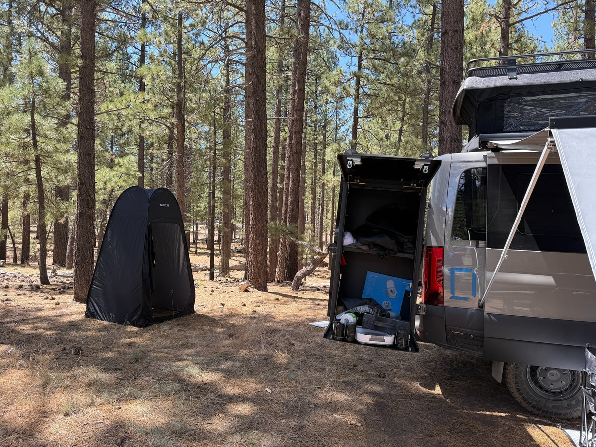 perfect for rv rental trips.|Grey camper van RV rental in a pine forest campsite with an extended awning — photo 12