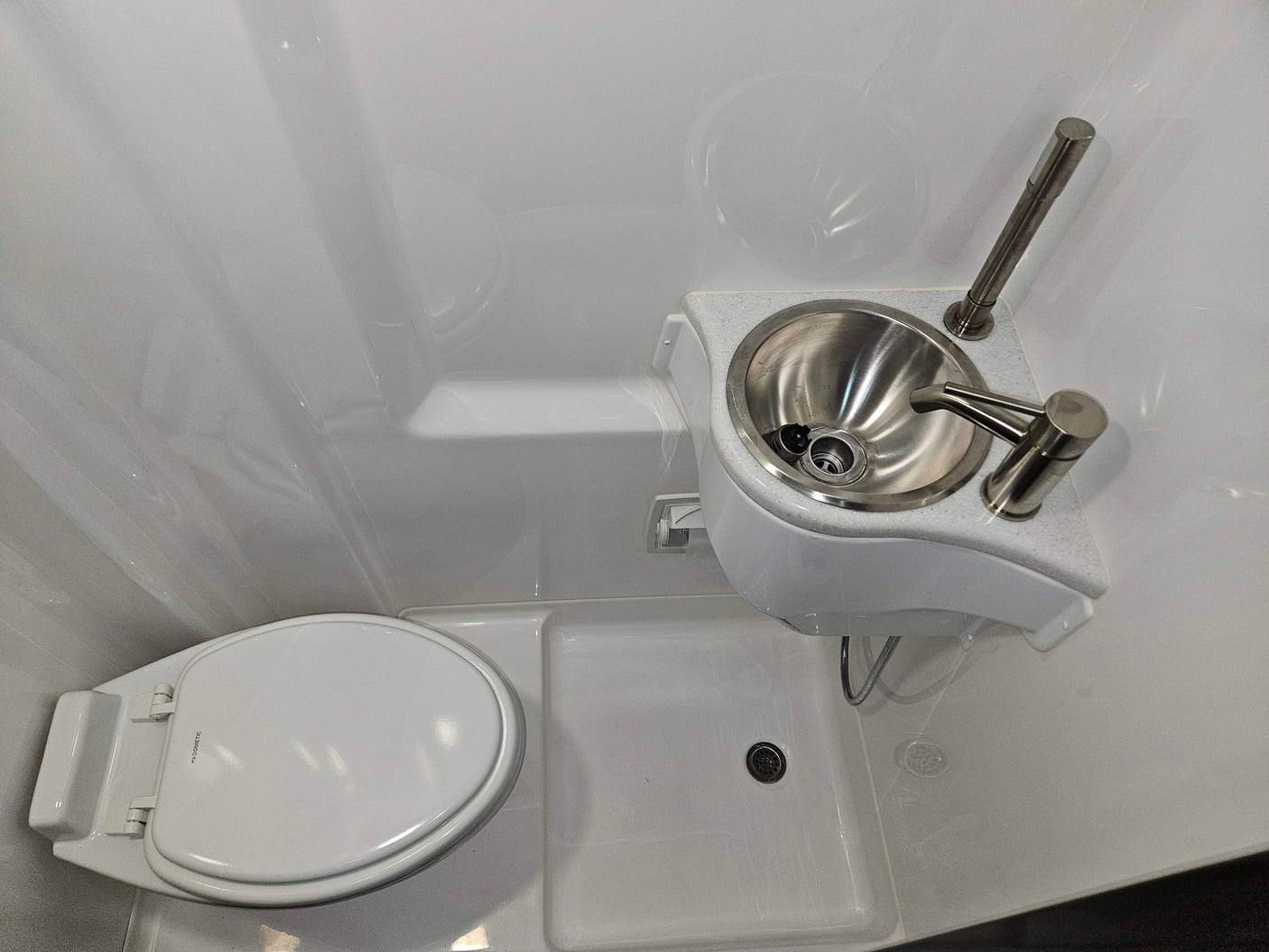 Compact RV rental wet bath with toilet, sink, and shower in one space, perfect for small living.