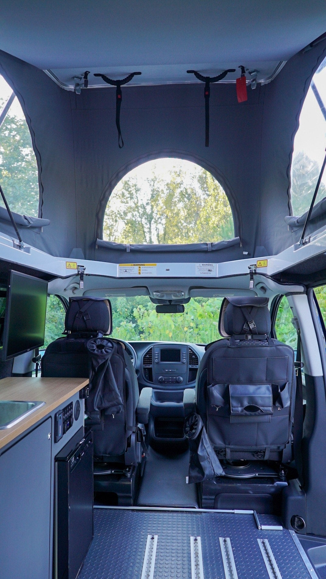 is set up with chairs & table on grass by a forest.|RV rental's spacious interior — photo 7