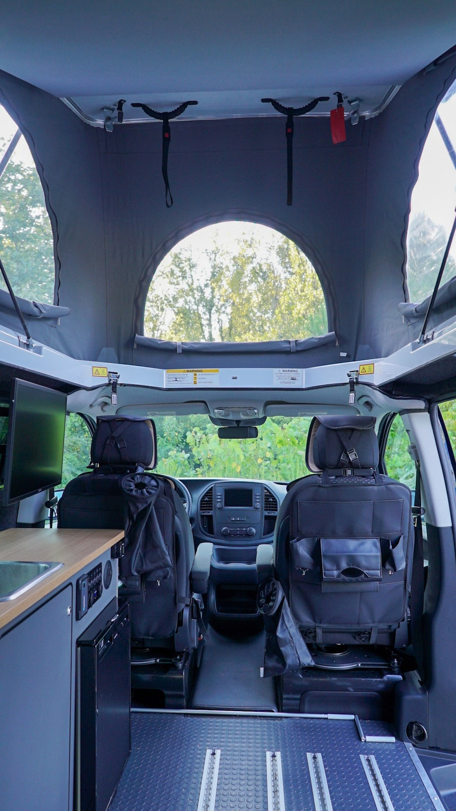 is set up with chairs & table on grass by a forest.|RV rental's spacious interior