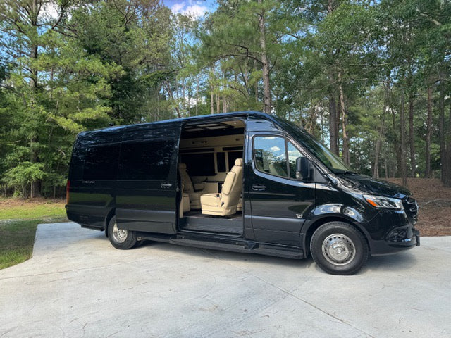 ready for your next rv rental adventure. Parked on a sunny driveway with trees.|Luxury black Mercedes-Benz Sprinter rv rental van. Side door open revealing plush tan seating