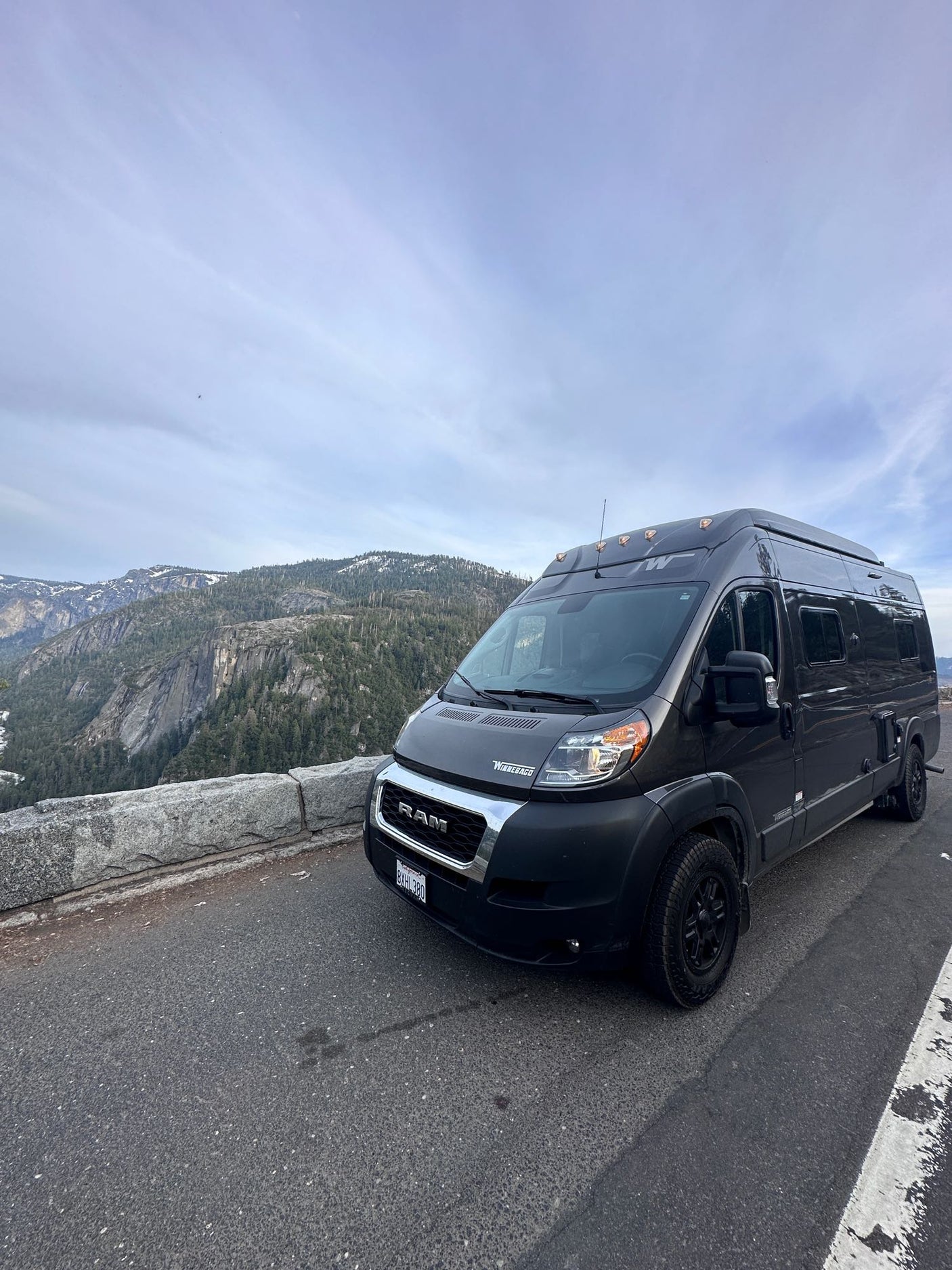 Dark gray Winnebago rv rental parked at a scenic mountain overlook, offering stunning valley views.