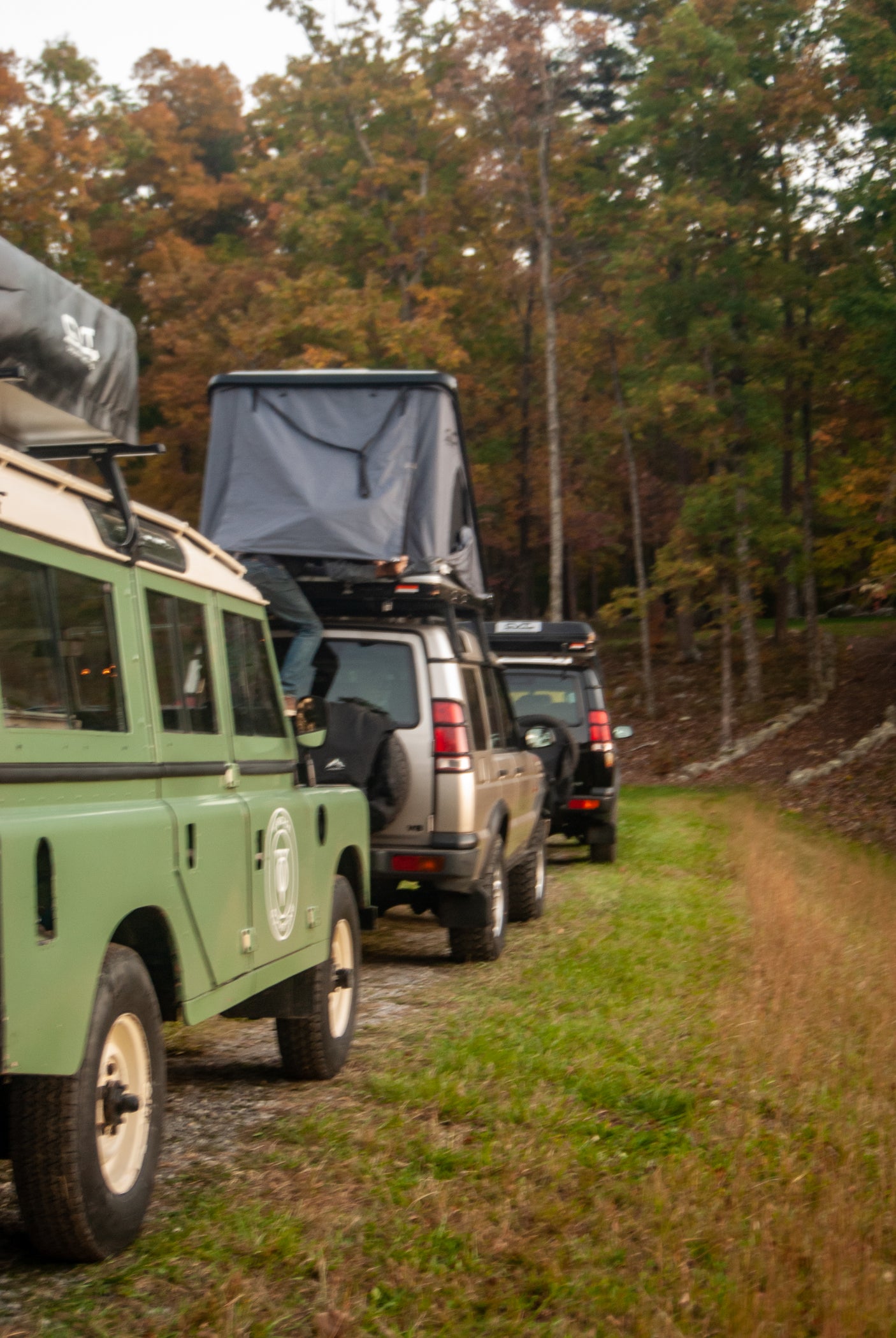 Green, silver, and black Land Rovers with rooftop tents, parked on a path. Great for an RV rental adventure!