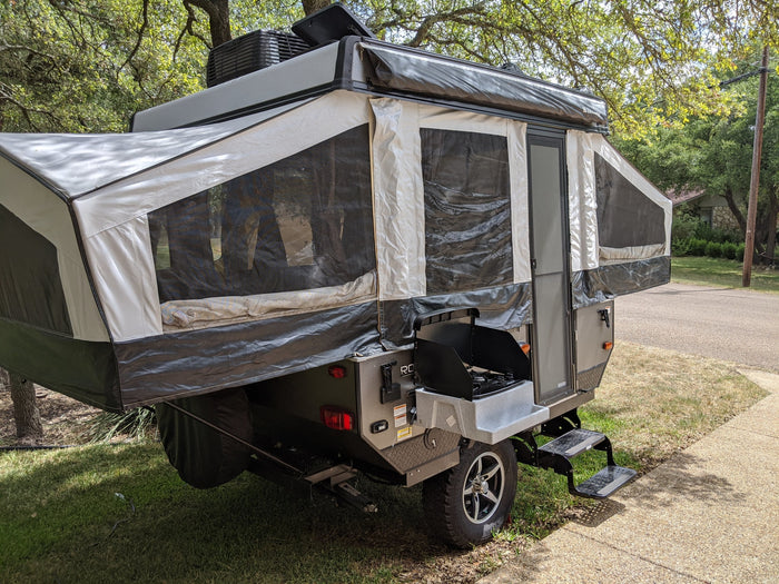 This spacious pop-up camper, perfect for RV rental, features an outdoor kitchen and extended canvas sleeping areas.