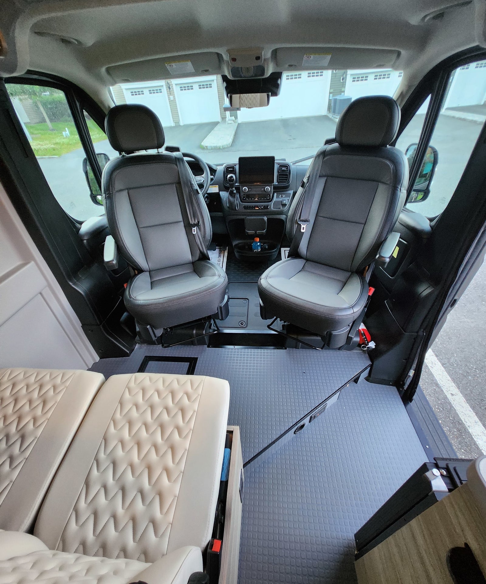 overlooking a serene body of water.|RV rental interior: spacious cockpit with dark seats & dashboard