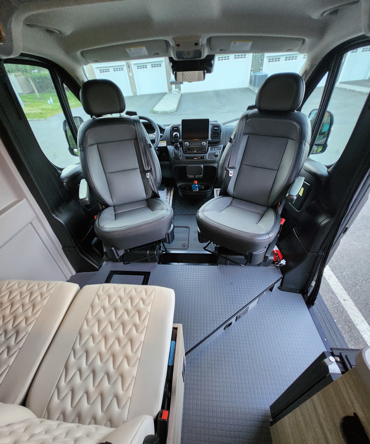 overlooking a serene body of water.|RV rental interior: spacious cockpit with dark seats & dashboard
