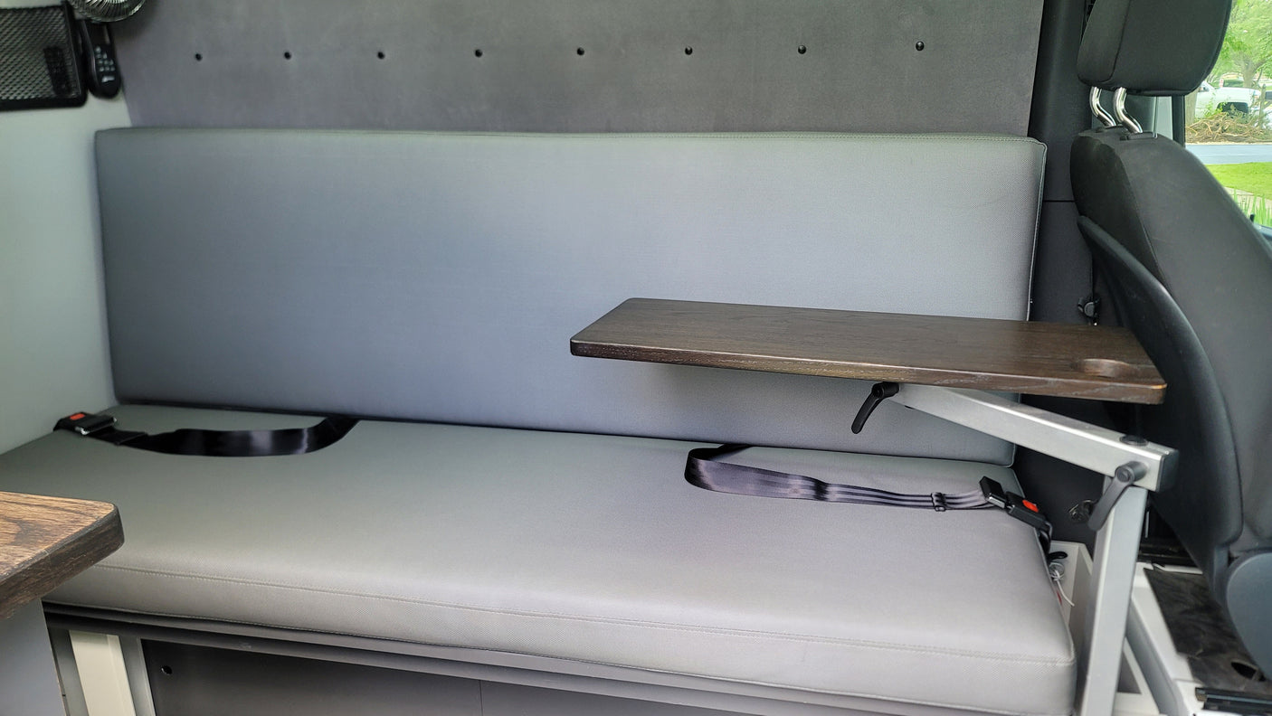Comfortable RV rental interior with grey bench seating, adjustable table, and seatbelts for travel convenience.