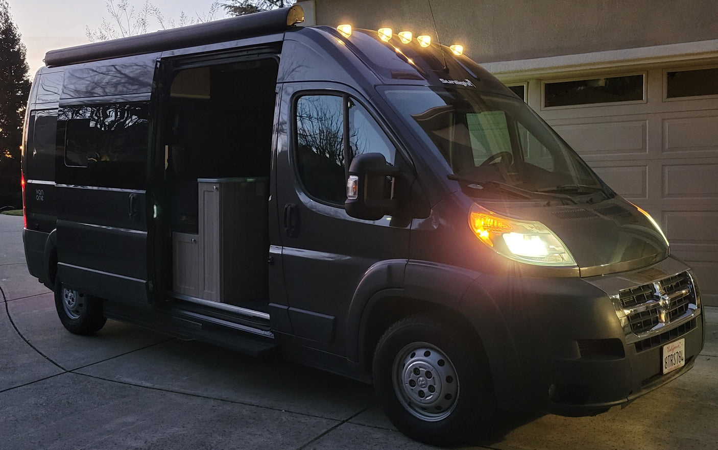 Explore in style! This modern grey camper van, ready for an RV rental adventure, shows its interior with lights on.