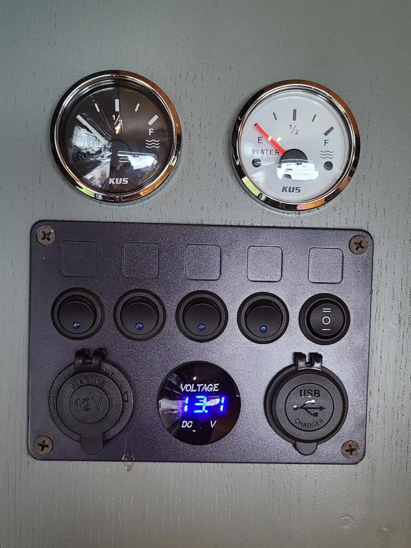 RV rental control panel: water gauges (KUS), voltmeter (13.1V), 12V/USB power ports, and rocker switches.