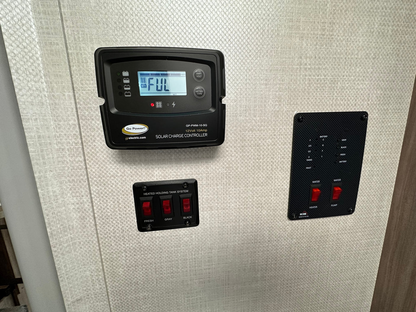 RV rental interior with control panels: Go Power solar charge controller (full battery), heated tank system, and water pump/heater controls.