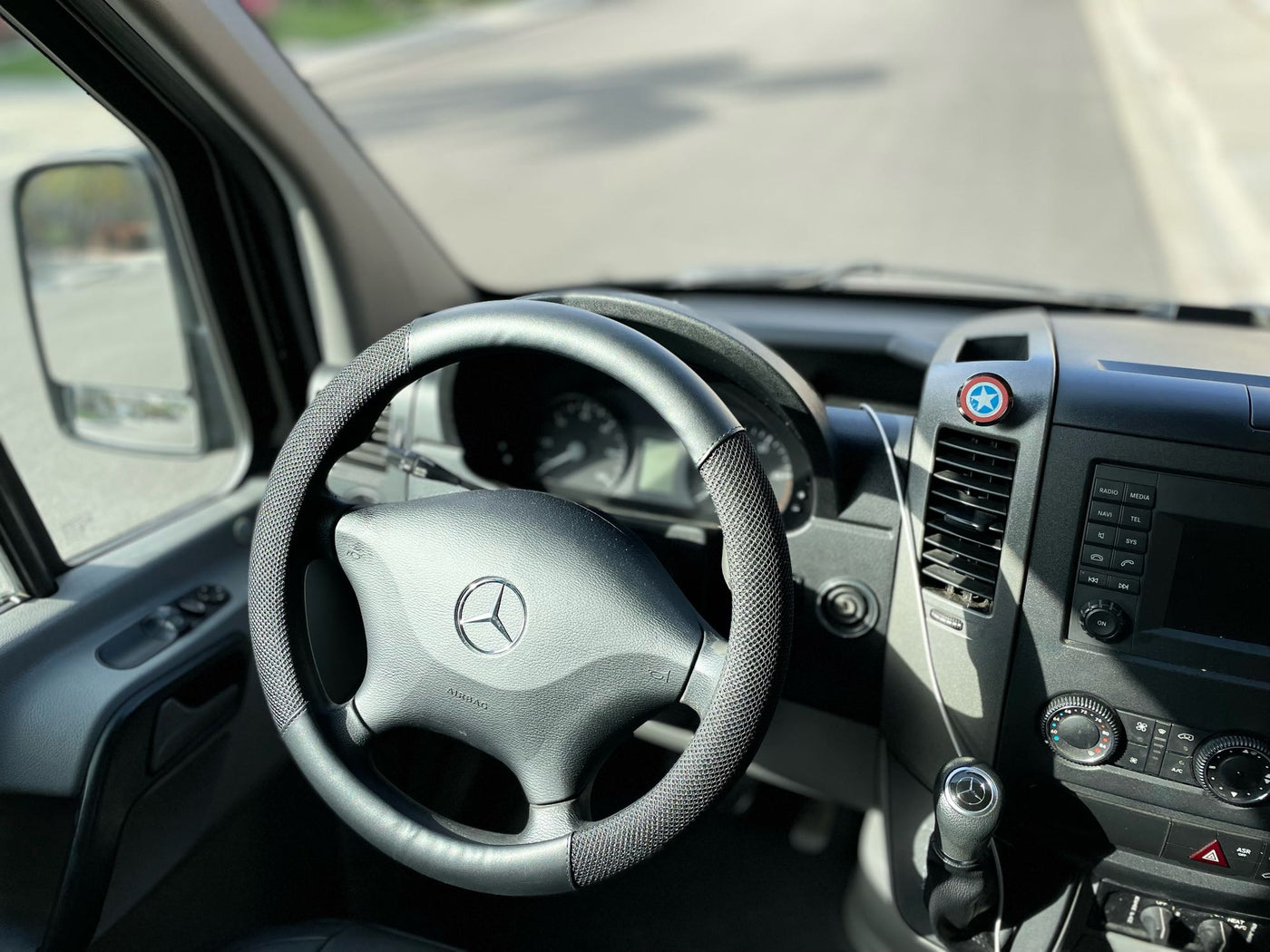 RV rental interior: Mercedes-Benz steering wheel, dashboard, and a Captain America shield emblem. — photo 12