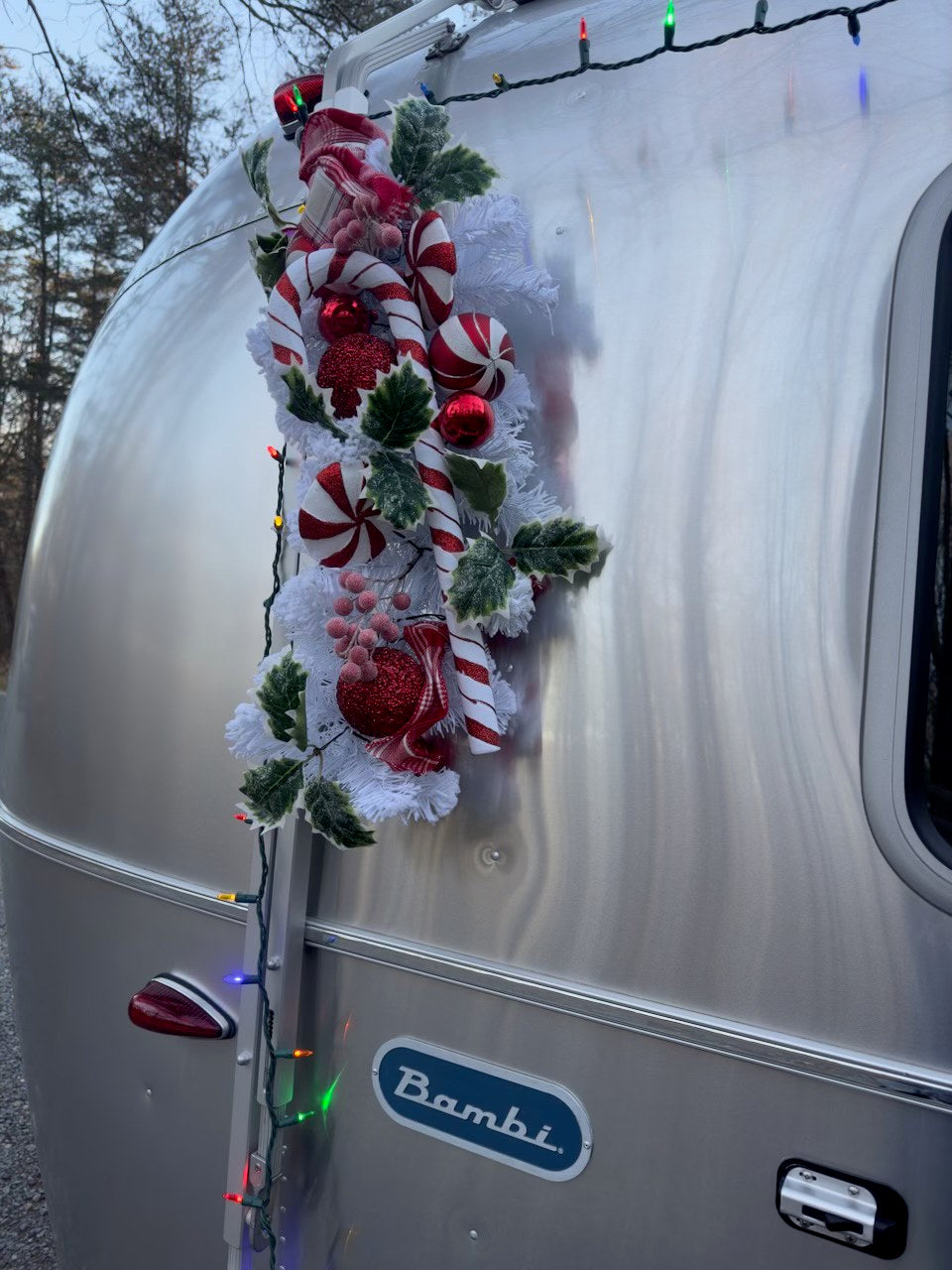Festive Airstream Bambi RV rental decorated for holidays with candy canes, ornaments, and lights. Perfect for a cozy getaway!