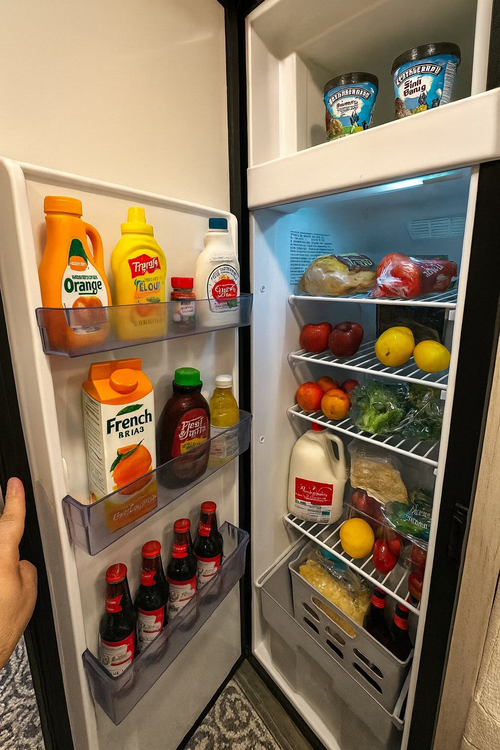 Open rv rental fridge: ice cream, fruit, veggies, milk, condiments, and beer. Ready for your travel journey!