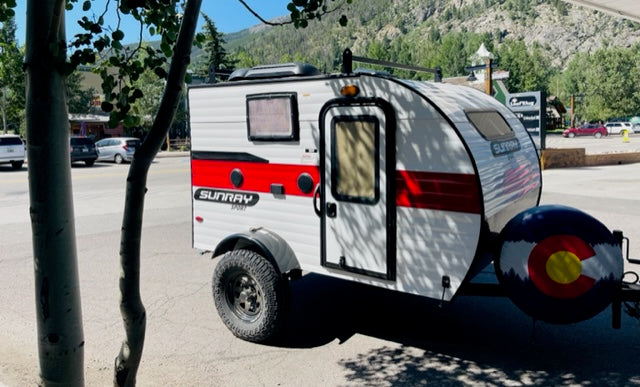 Explore Colorado! This Sunray Sport teardrop camper RV rental with a Colorado flag spare tire cover is perfect for your next adventure.