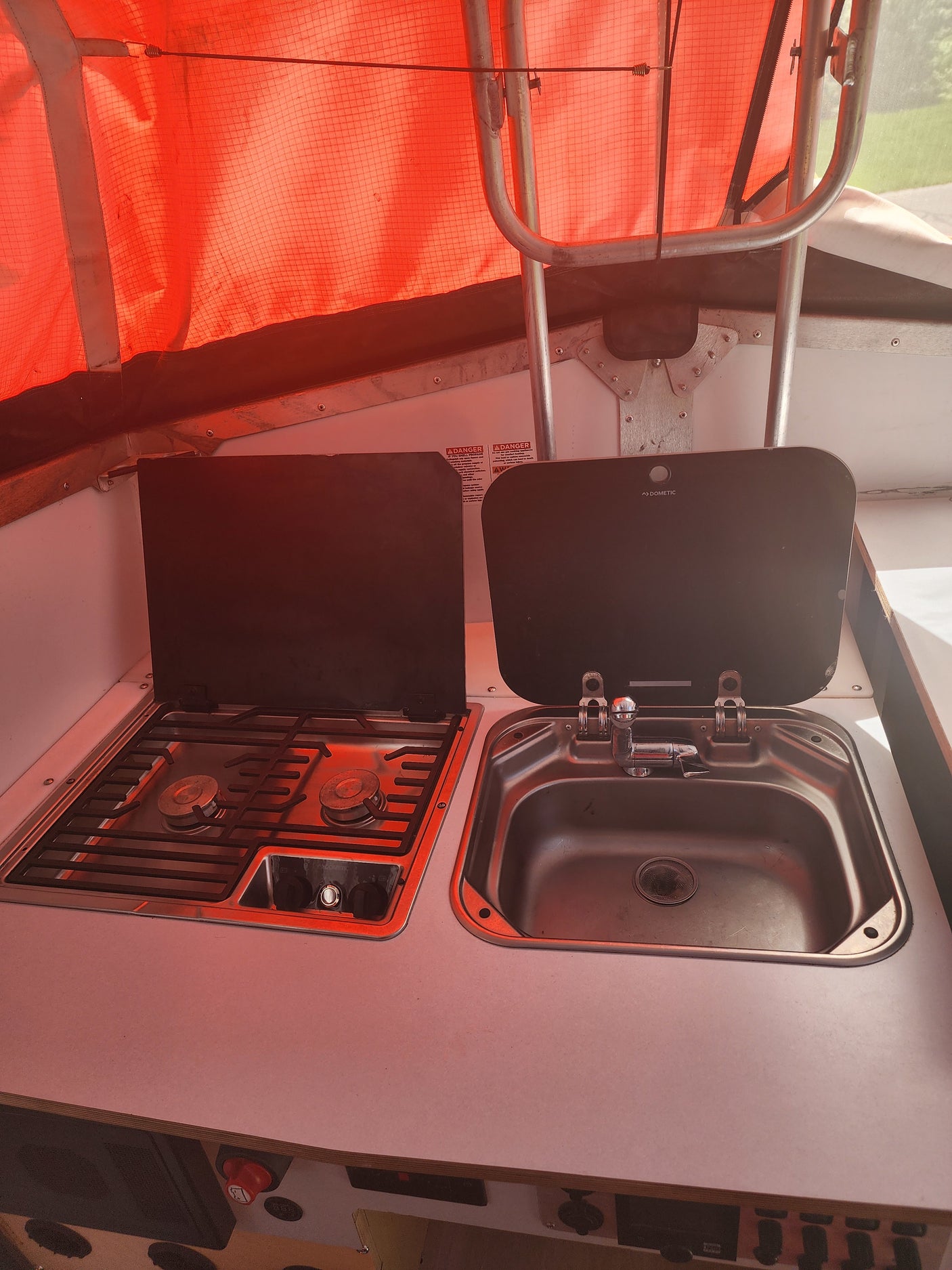 Inside a Dometic-equipped RV rental: compact kitchen with two-burner stove & sink unit. Ideal for camping.