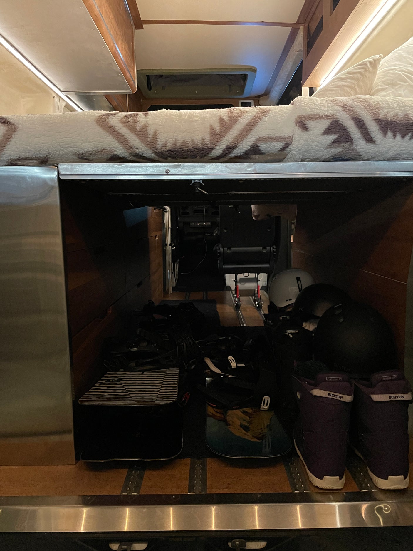 RV rental interior: Under-bed storage packed with snowboards, helmets, and boots. Ready for adventure!