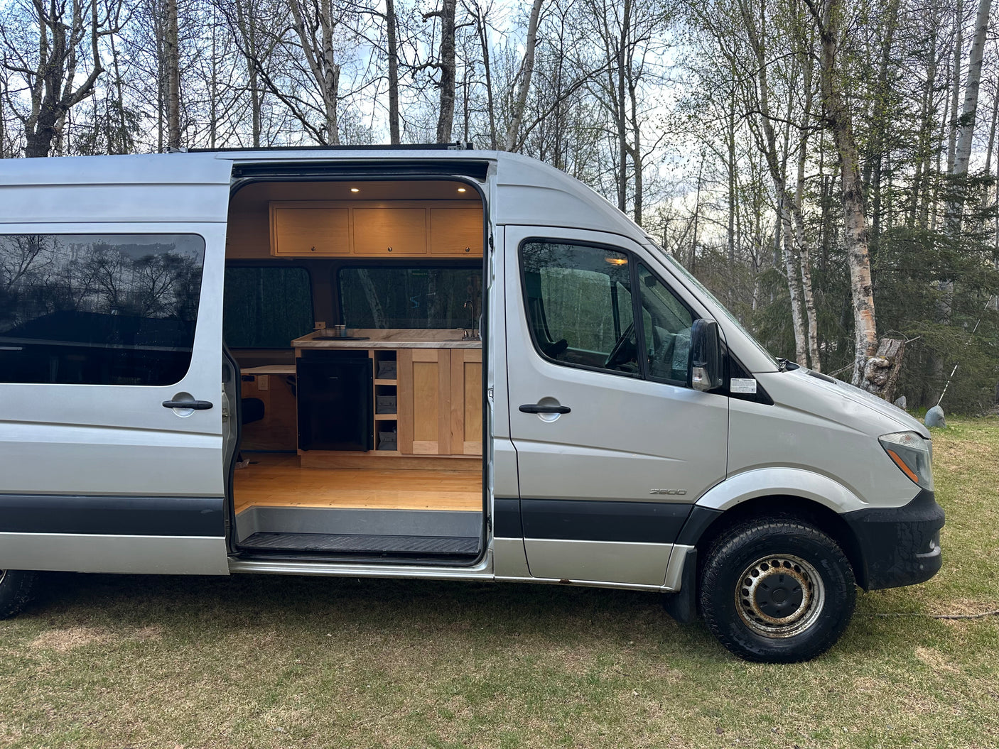 Inside an RV rental: a silver camper van with a beautifully crafted wood kitchen and interior, ready for adventures.