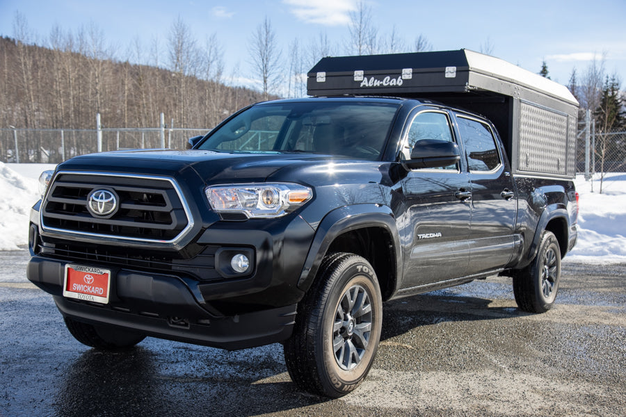 Black Toyota Tacoma overland rig with Alu-Cab camper, perfect for an RV rental adventure.