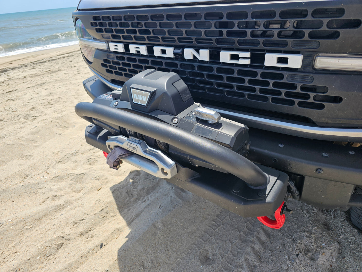 Bronco with WARN winch on a sandy beach. Ideal for off-road adventures, similar to an RV rental trip.