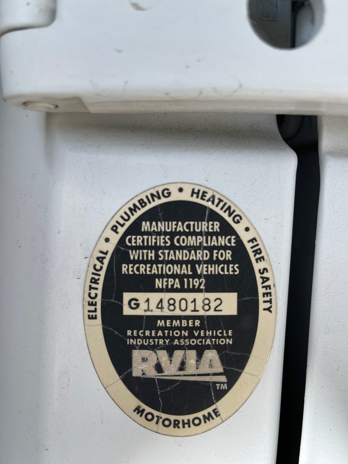 Close-up of an rv rental's RVIA certification, detailing compliance for electrical, plumbing, heating, and fire safety.
