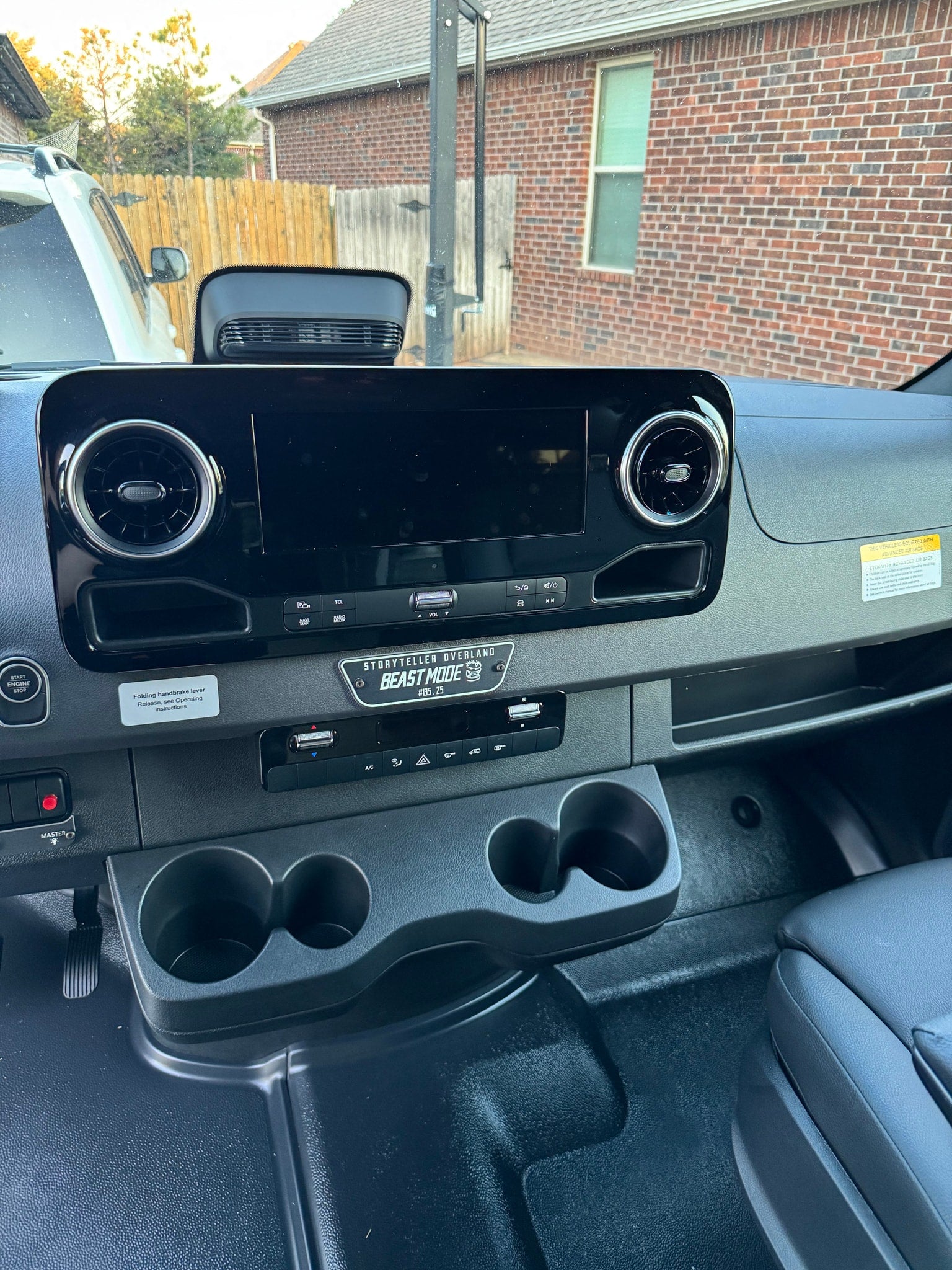 Inside a Storyteller Overland RV rental, showing the dashboard with screen, "Beast Mode" plate, climate controls, and cup holders.
