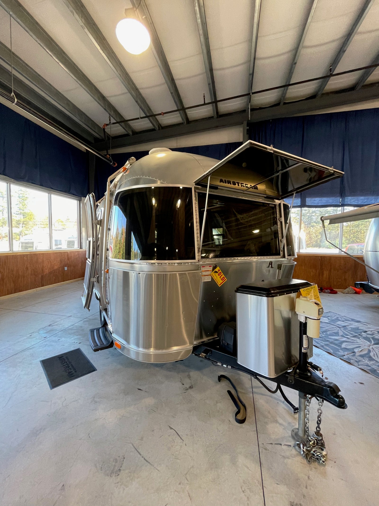 Polished Airstream travel trailer (RV) on display, ideal for your next rv rental adventure. Its front window guard is open.