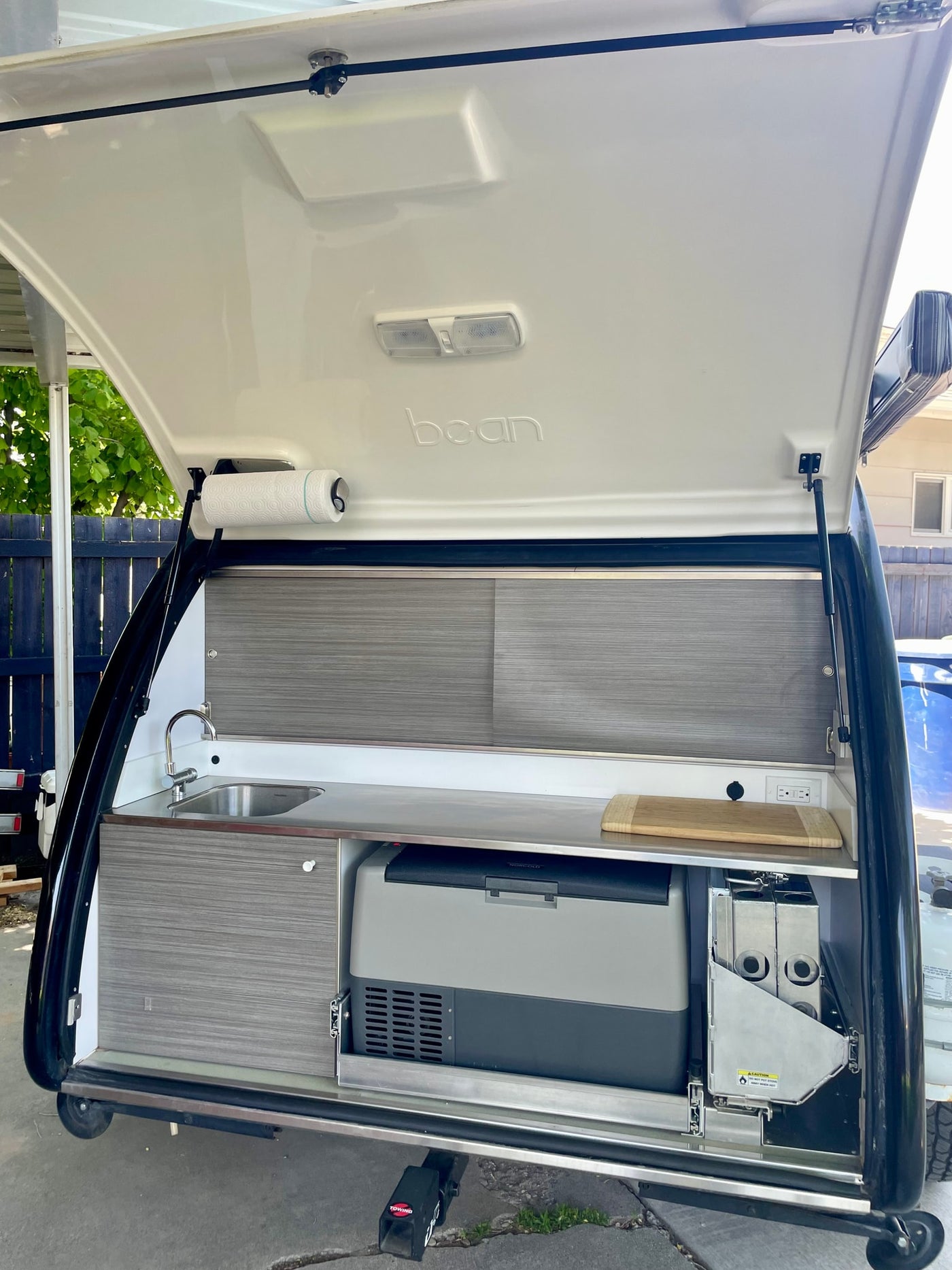 Explore this modern RV rental teardrop trailer's rear galley, featuring a sink, Norcold fridge, and pull-out stove. — photo 1