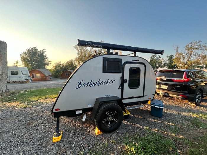 at an RV rental site with a snow-capped mountain backdrop.|Bushwhacker teardrop travel trailer