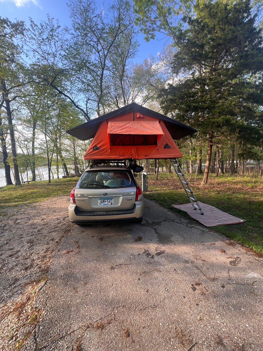 Rooftop tent camping with a Subaru Outback by the water, a compact option instead of an RV rental for outdoor adventure.
