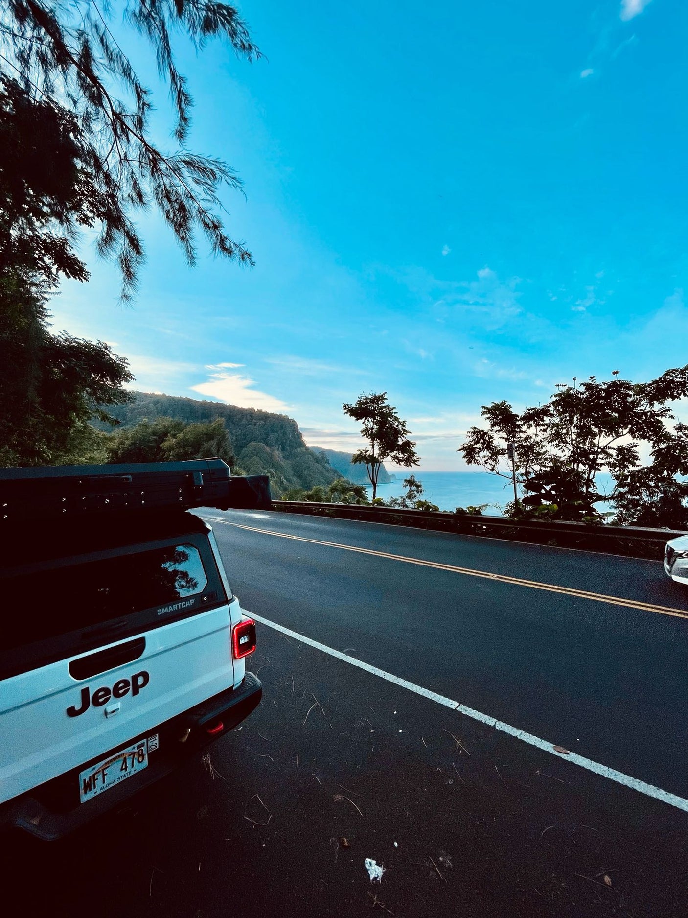 & beach views for your next outdoor trip.|A white Jeep truck with a camper top is parked on a scenic coastal road