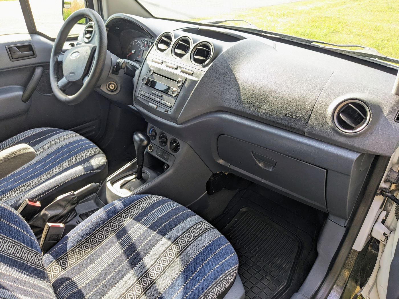 Interior of an RV rental van, showing the dashboard, steering wheel, and front seats with unique blue patterned covers.