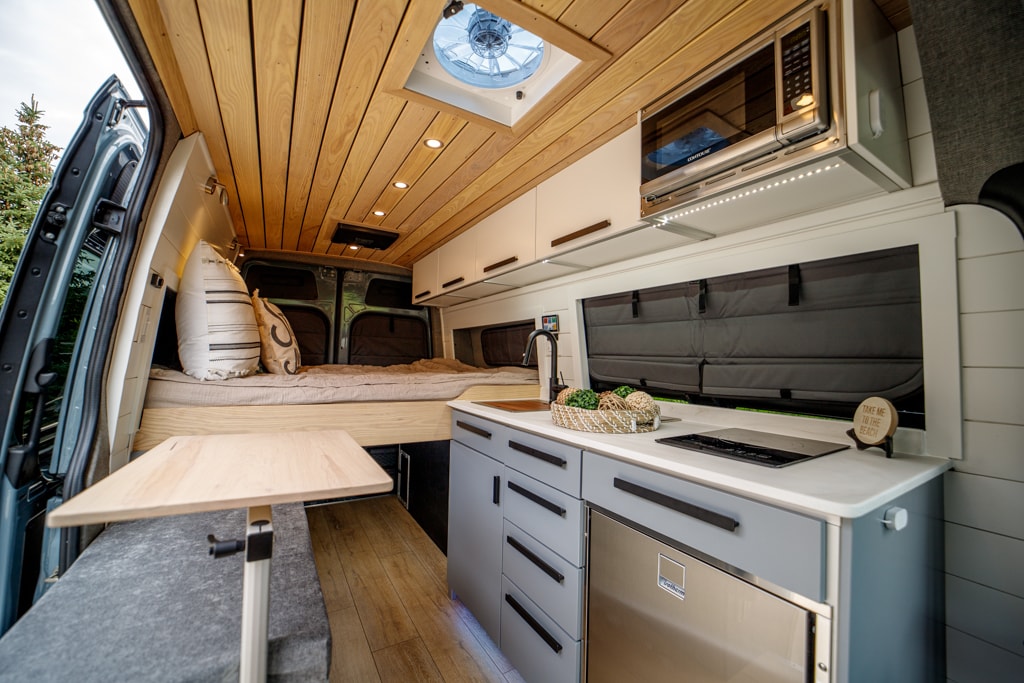 ready for adventure under a clear sky.|Spacious custom RV rental interior: elevated bed — photo 10