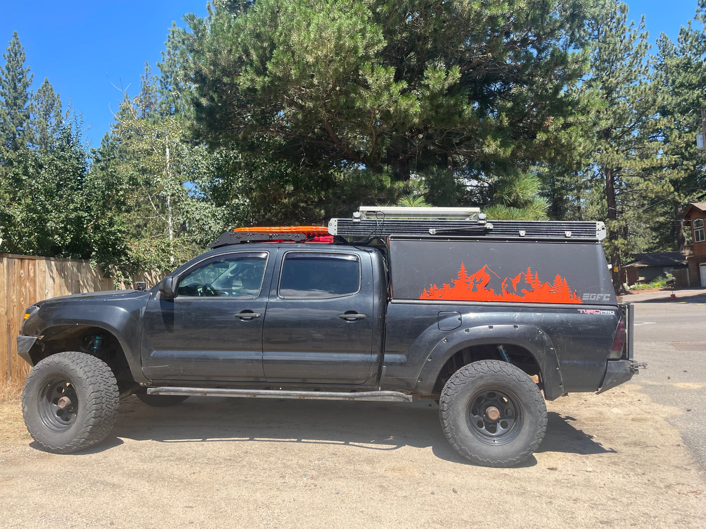 This black overlanding Toyota Tacoma pickup truck with a pop-top camper, ideal for RV rental adventures, is ready for off-road camping.