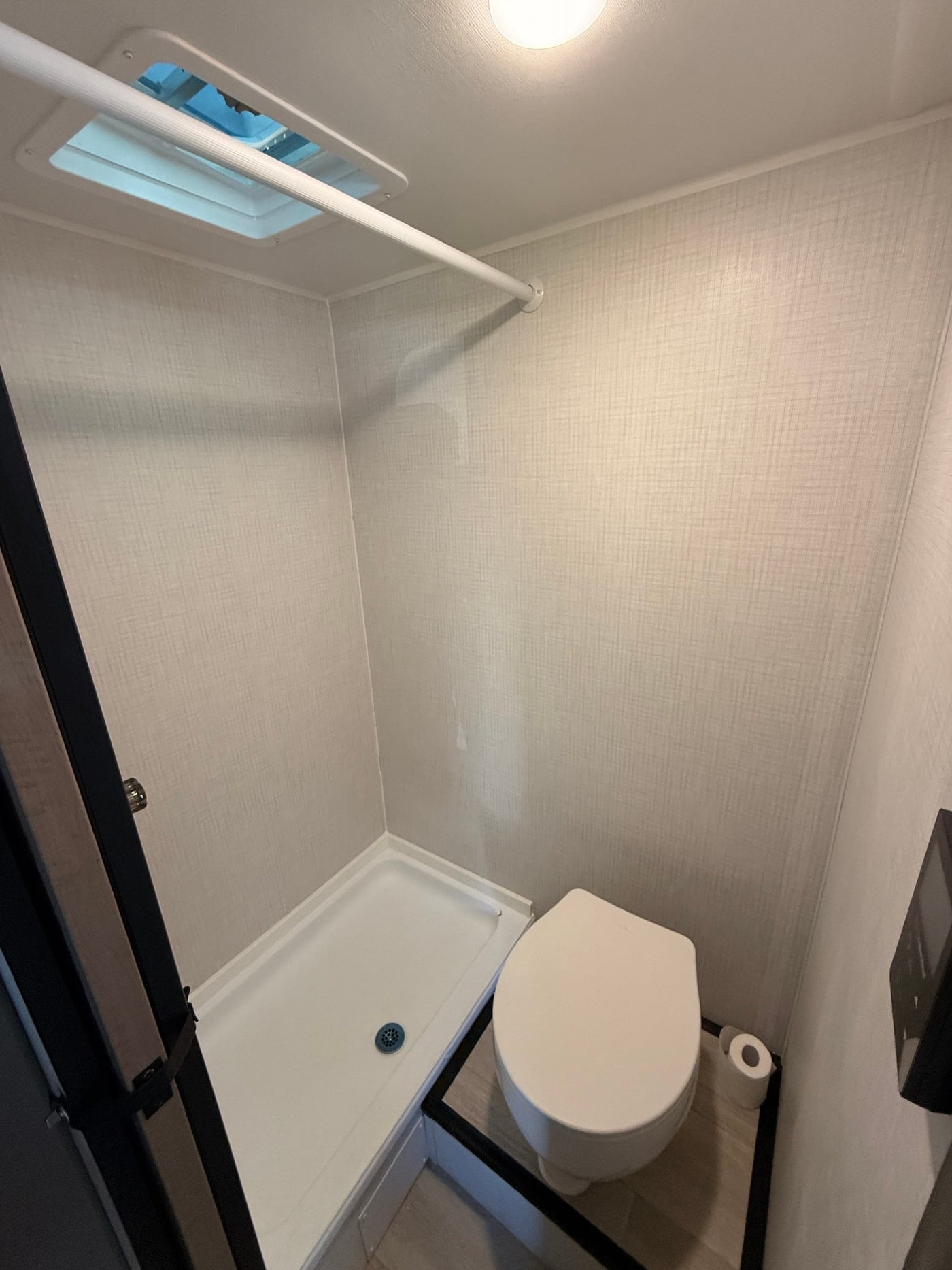 This RV rental's compact bathroom features a shower, toilet, and overhead skylight, designed for efficient use of space. — photo 6