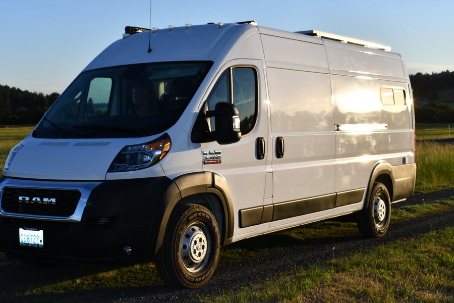 White Ram Promaster van, converted into an RV rental, shines in golden light, ready for camping & exploration.