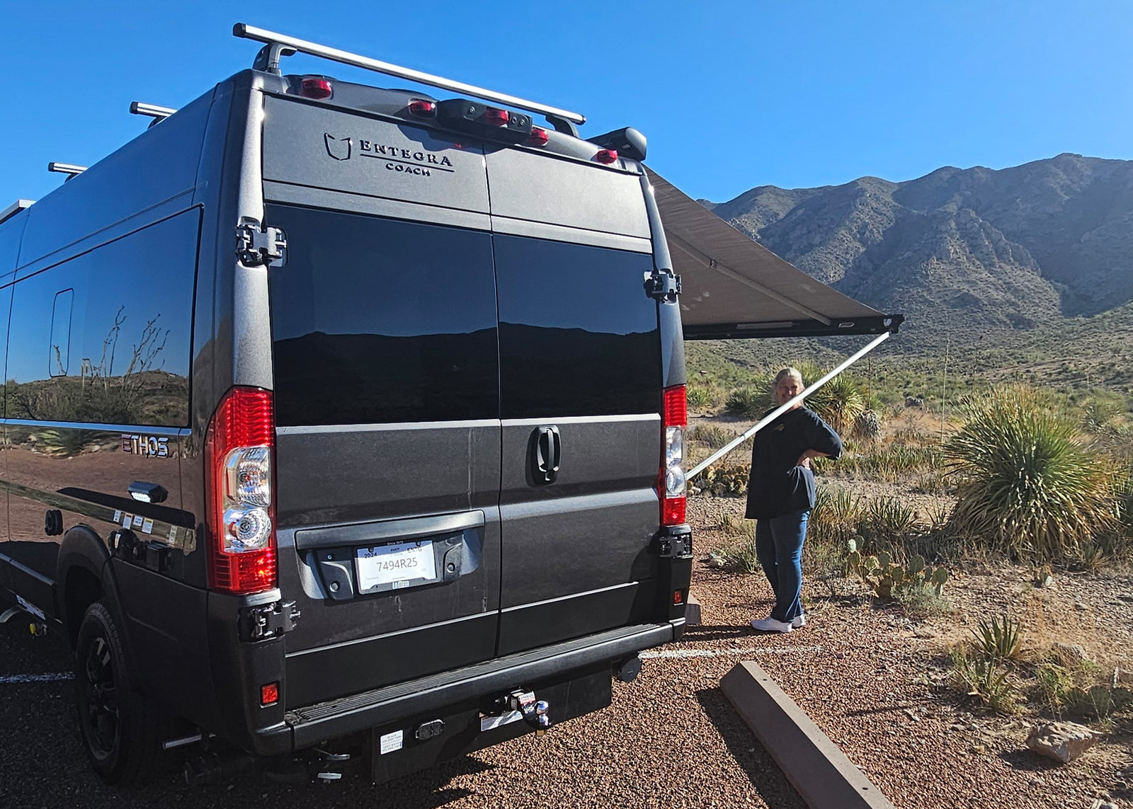 ideal for an rv rental adventure.|Black camper van with an extended awning parked on gravel. Ideal for rv rental adventures in desert landscapes.|Relaxing with an RV rental: a grey camper van with an extended awning