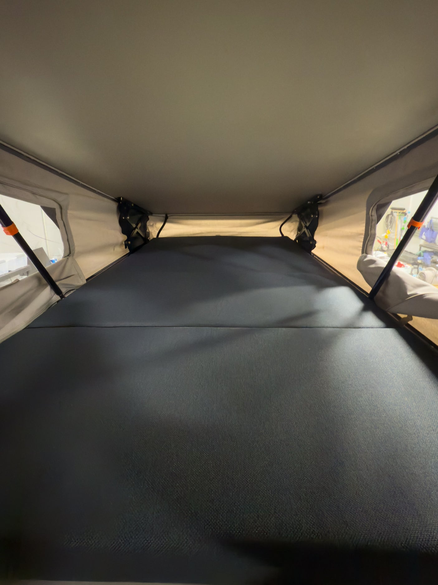 RV rental pop-up tent interior: a spacious sleeping area with a dark grey mattress.