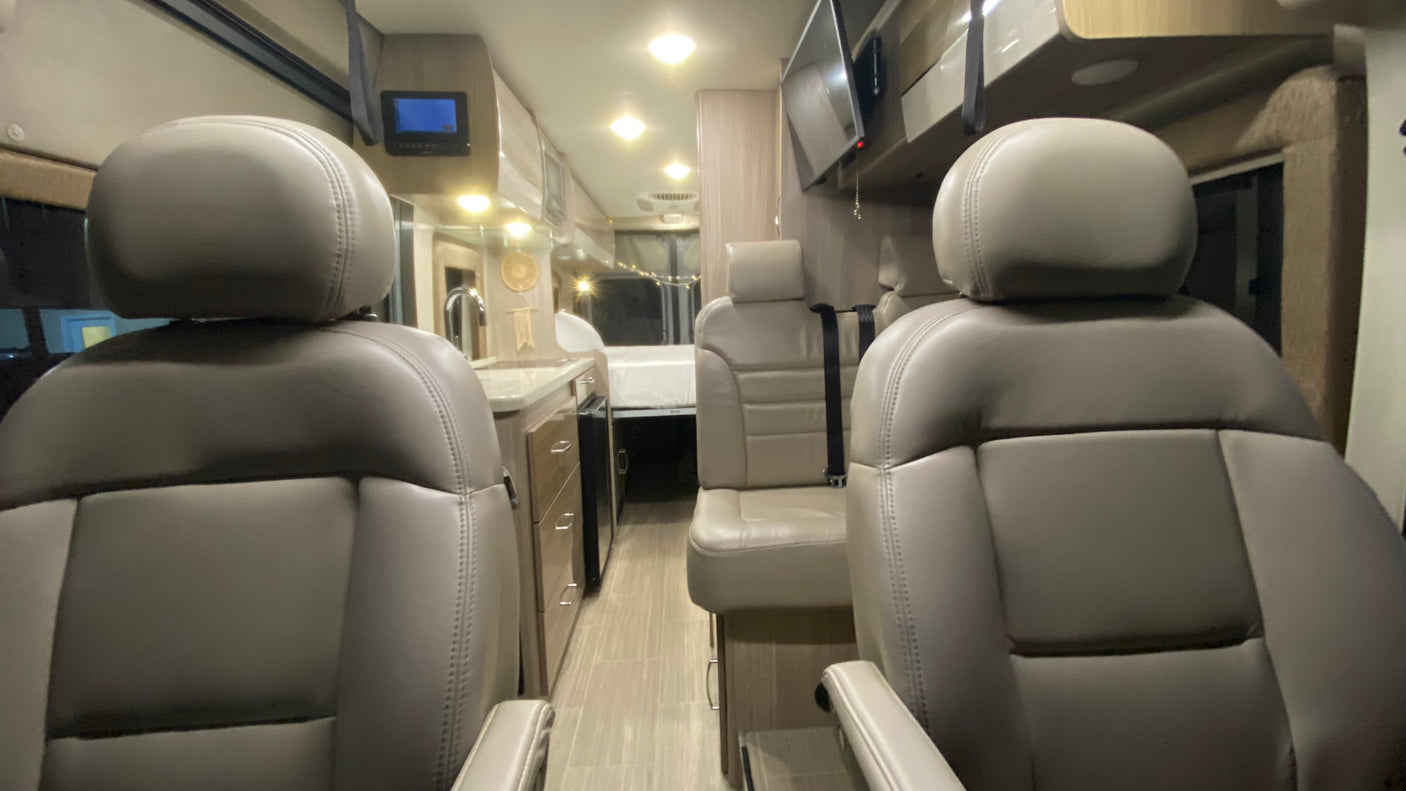 Step into this RV rental's inviting interior, revealing comfortable seats, a functional kitchen, and a rear sleeping area.
