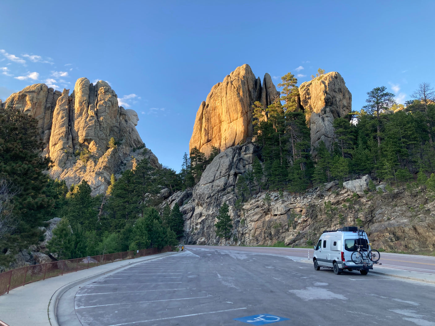 An RV rental parked at Mount Rushmore National Memorial, with the carved presidential faces and rugged landscape visible.