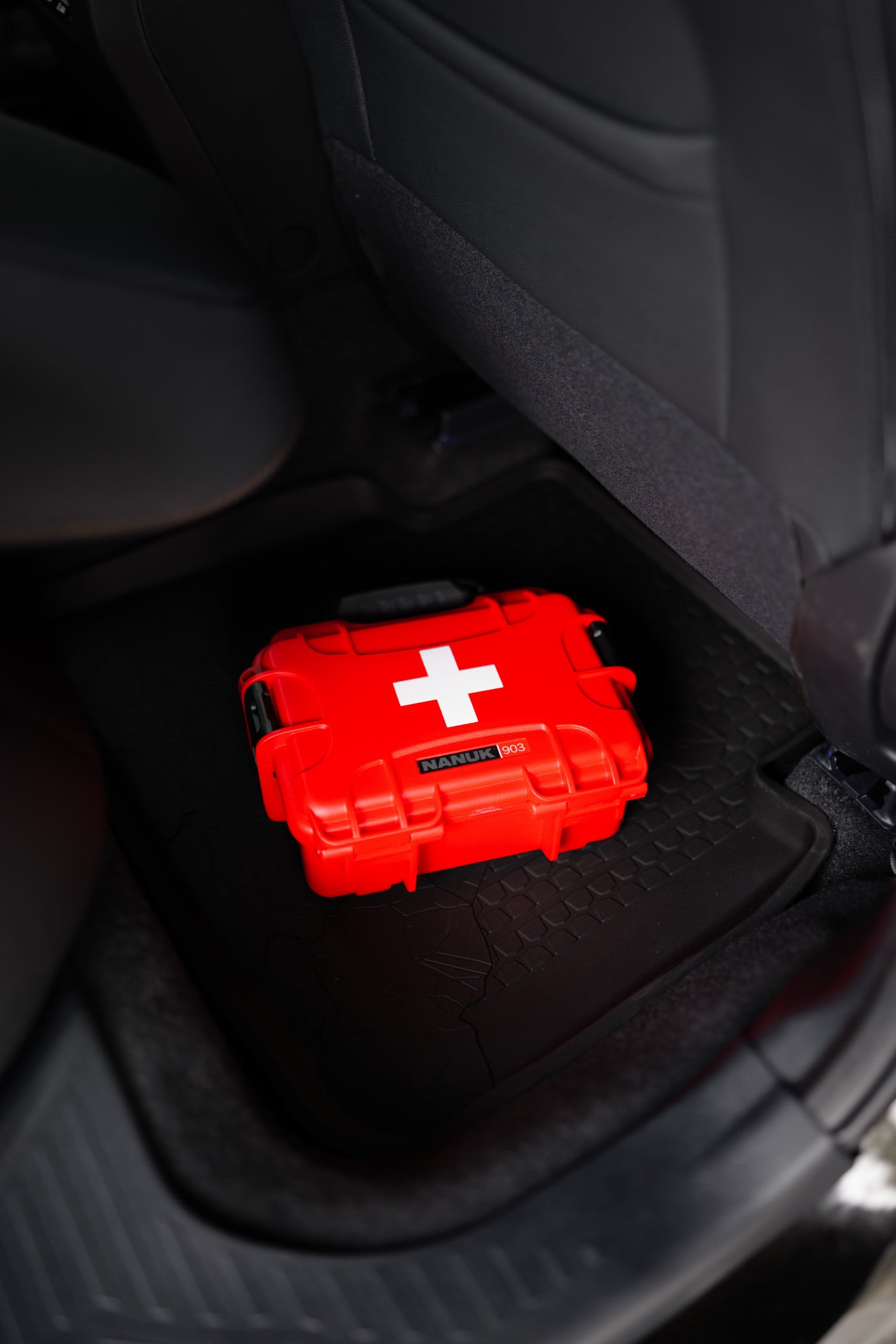 Essential red NANUK 903 first aid kit with white cross, ready on a rubber mat in an RV rental.