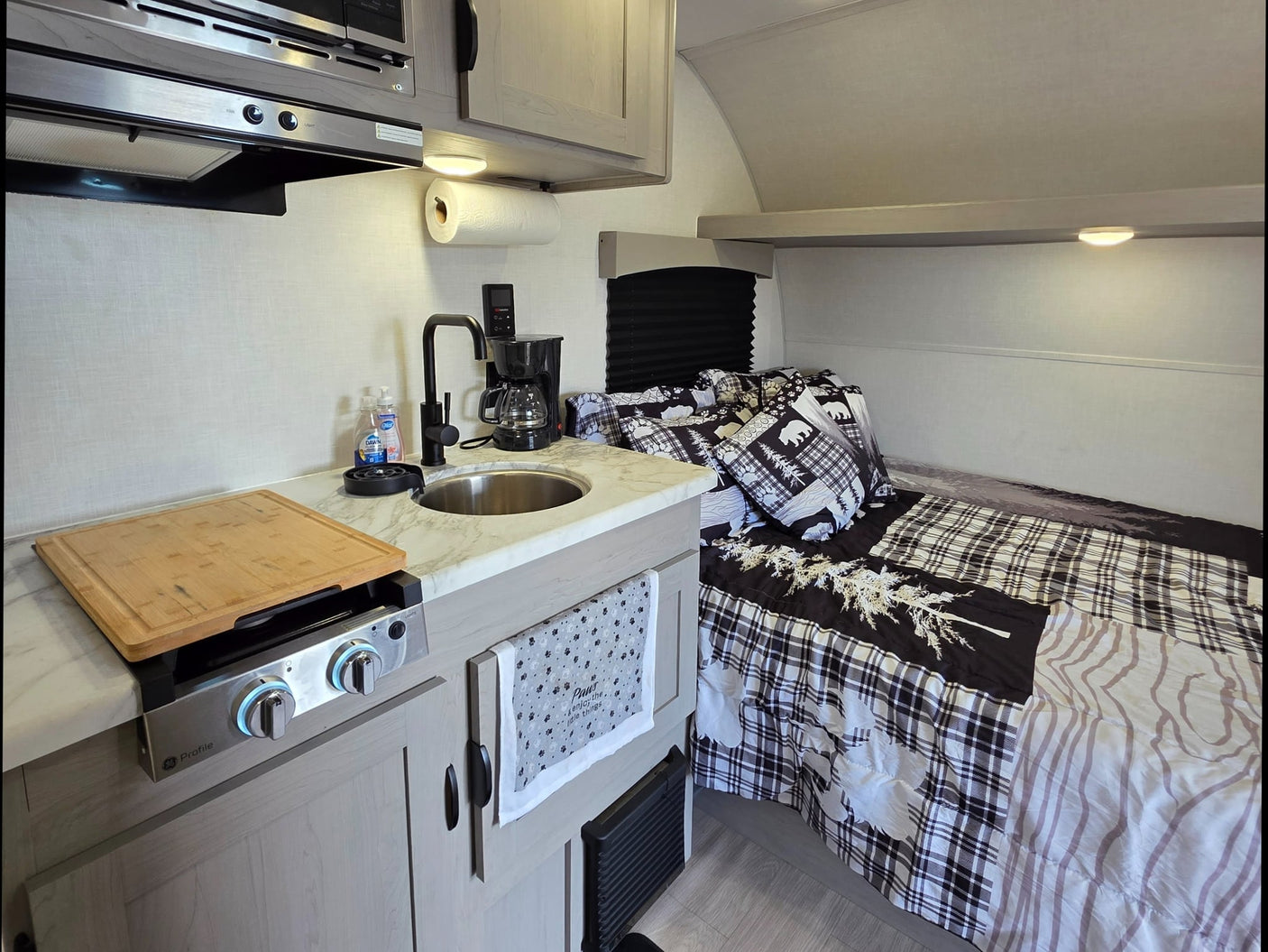 and fire pit under cloudy skies.|Cozy rv rental interior: compact kitchen with sink
